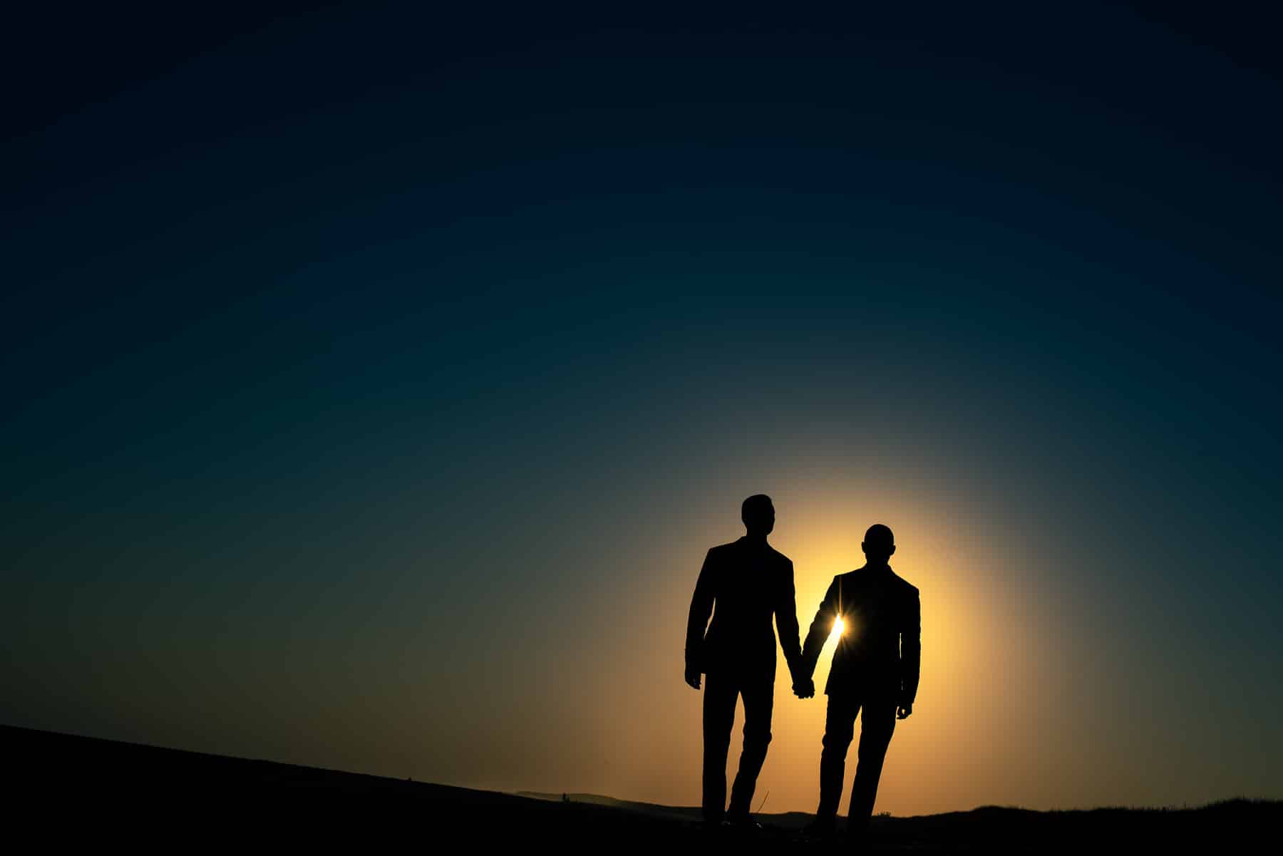 Gay couple walking into sunset